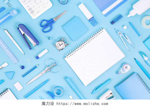 蓝色背景上的办公用品将办公室和学校的白色和蓝色文具和记事本分类，贴在胶粘的背景上。平躺在地上，有复制空间，可以回到学校或教育和手工艺的概念。蓝色单色横幅